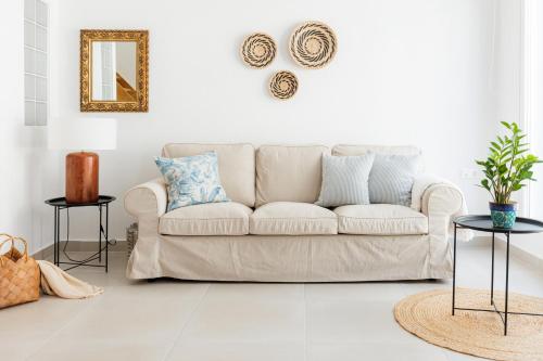 Sala de estar blanca con sofá y espejo en Helona guesthouse, Skopelos, en Skopelos Town