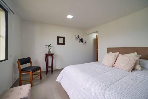 a bedroom with a bed with pink pillows and a chair at Monte Hermoso - Apartamento campestre in Guatapé