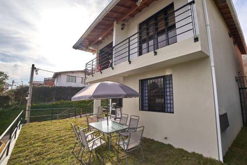 a table and chairs with an umbrella in front of a house at Monte Hermoso - Apartamento campestre in Guatapé