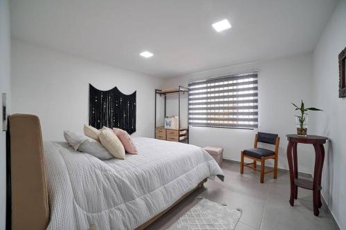 a bedroom with a bed and a table and a chair at Monte Hermoso - Apartamento campestre in Guatapé
