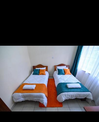 2 łóżka w małym pokoju z oknem w obiekcie House 469 w mieście Nairobi