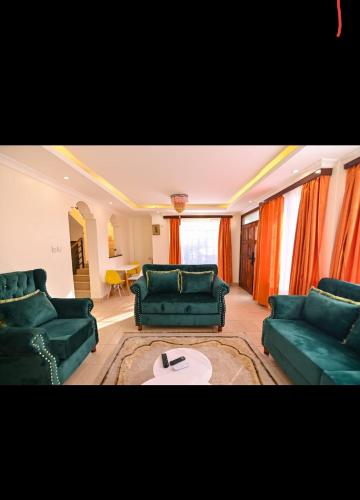un soggiorno con mobili verdi e tende arancioni di House 469 a Nairobi