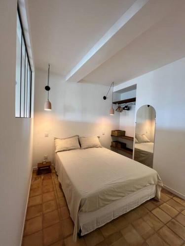 sypialnia z białym łóżkiem i lustrem w obiekcie Bormes - Le Loft w mieście Bormes-les-Mimosas