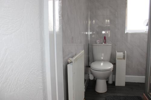 a white toilet in a bathroom with a window at Cosy Home Ideal for Business, Contractors, Families near Walsgrave Hospital, Shops and M6, A46, Free Parking in Wyken