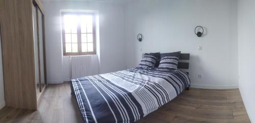 1 dormitorio con cama con sábanas a rayas y ventana en Gite 6 personnes Sarlat/Rocamadour, en CazoulÃ¨s