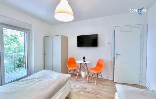 a bedroom with two orange chairs and a table at BEGE APARTMENTS: PERFECT FOR COMPANIES in Gelsenkirchen