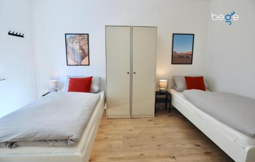 two beds in a room with white walls and wood floors at BEGE APARTMENTS: PERFECT FOR COMPANIES in Gelsenkirchen