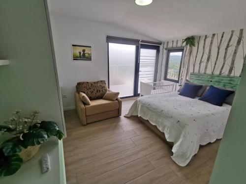 a bedroom with a bed and a chair and a window at O Recuncho de Tibias in Pereiro de Aguiar