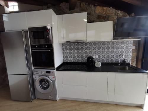 a white kitchen with a refrigerator and a microwave at O Recuncho de Tibias in Pereiro de Aguiar