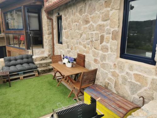 a patio with a table and chairs and a grill at O Recuncho de Tibias in Pereiro de Aguiar