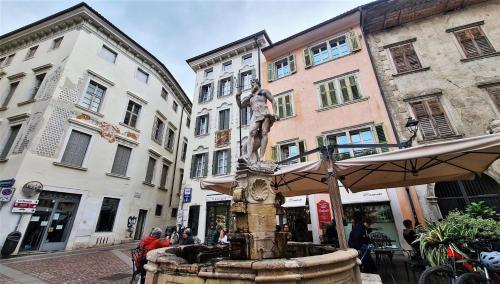 a fountain in the middle of a street with buildings at Mazzini, 30 Nord in Rovereto