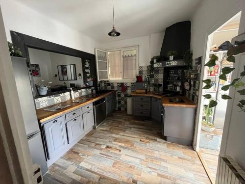 a kitchen with white cabinets and a wooden floor at Maison typique Maillé 
