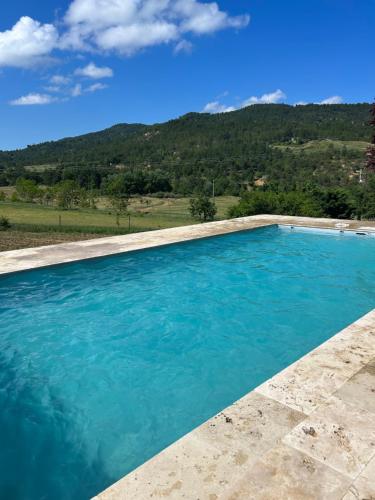 a pool of blue water with a mountain in the background at Domaine de Prefaissal in Mézel