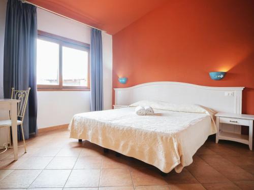 a bedroom with a bed with an orange wall at Hotel Pedra Santa in Baja Sardinia