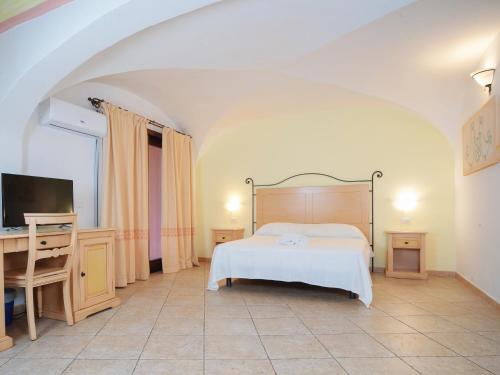 a bedroom with a bed and a desk and a tv at Hotel Pedra Santa in Baja Sardinia