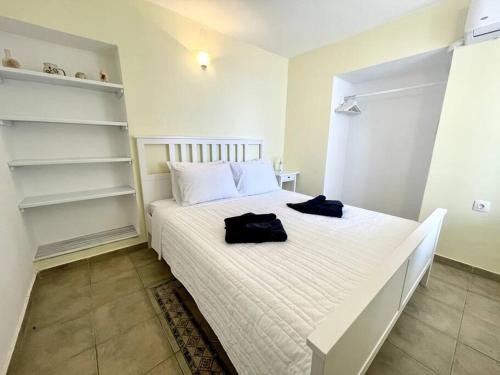 a bedroom with a bed with white sheets and shelves at Sunset Haven in Poros