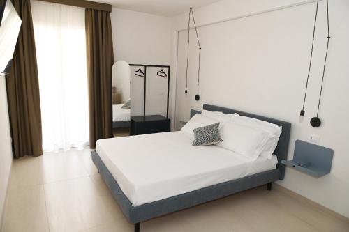 a bedroom with a bed with white sheets and a mirror at Lebum Apartments & Suites in Marsala