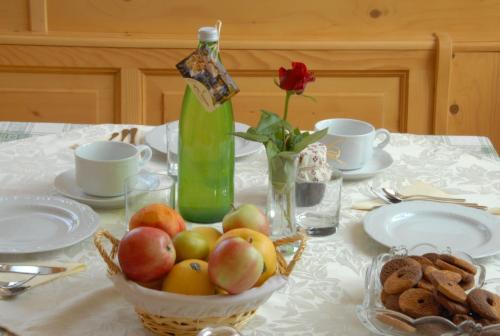 a table with a bowl of fruit and a bottle of wine at Agritur Widmann in Coredo