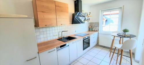a kitchen with white cabinets and a sink and a table at Apartments In Spay BigOne Zell-Merl Mosel in Zell an der Mosel