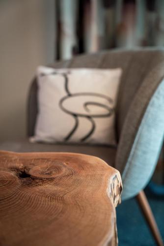 a couch with a pillow and a wooden table at Kulinarik & Geniesser Hôtel STRAUSS in Fiesch