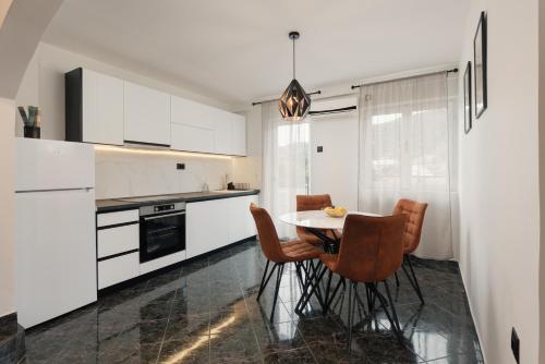 a kitchen with white cabinets and a table and chairs at Sea Breeze in Kotor