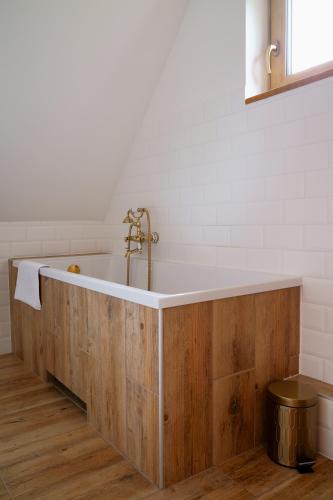 y baño con bañera de madera grande y paredes blancas. en Country house, en Dziemiany