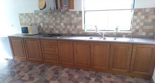 a kitchen with wooden cabinets and a sink and a window at Cantinho Verde in Sertã