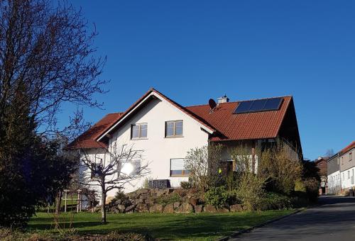 a white house with a roof with solar panels on it at Ferienwohnung Rhön Verliebt in Abtsroda