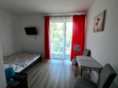 ブワディスワボボにあるGościWitaのベッドルーム1室(ベッド1台付)、赤いカーテン付きの窓が備わります。