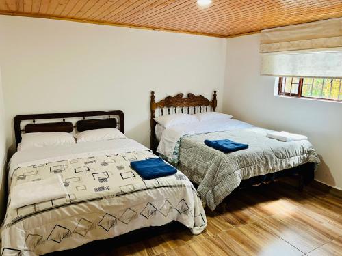 two beds in a room with white walls and wood floors at Hostal Agroturistico Guadalupe in Saboyá