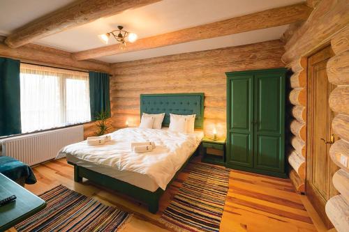 a bedroom with a bed in a room with wooden walls at Casa Boiereasca Bucovina in Gura Humorului