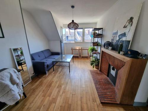 un salon avec un canapé bleu et une cheminée dans l'établissement Amiens - Appartement vue Cathédrale, à Amiens