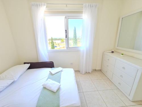 una camera con un letto bianco e una finestra di Stunning views' Apartment with Pool a Paphos