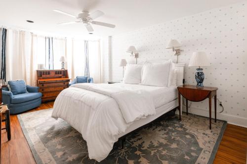 a bedroom with a large white bed and a blue chair at Rhett House in Beaufort