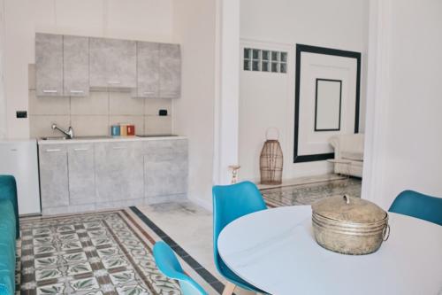 a dining room with a white table and blue chairs at Appartamenti Luxury Greco in Brindisi