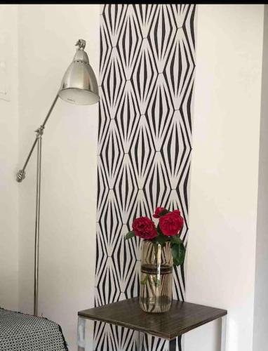 a vase with two roses on a table next to a lamp at Gîte de charme La Manola in Rognes