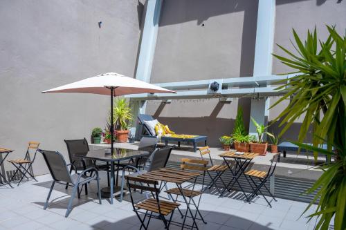 eine Terrasse mit Tischen, Stühlen und einem Sonnenschirm in der Unterkunft DuMont Lisbon Guesthouse in Lissabon