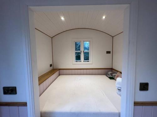 Cinderford的住宿－Tranquil Spot Shepherds Hut，一间白色的大房间,窗户在里面