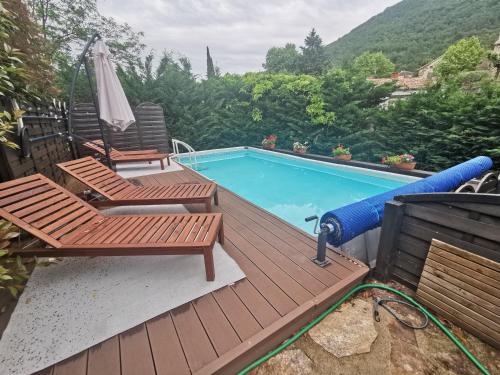 a deck with two chairs and a swimming pool at Mes Maisons Gardoises, Two Gites sleeping 13 with Two Private pools, Kids Room, Laundry, Disco, free WiFi, Linen and Dog's are Welcome in Gagnières