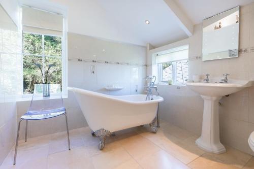 a white bathroom with a tub and a sink at Glenside House in Carbis Bay