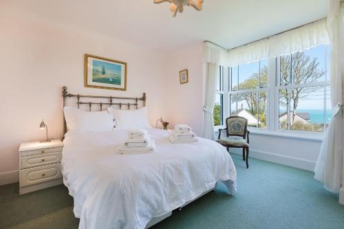 a bedroom with a large white bed with a window at Glenside House in Carbis Bay