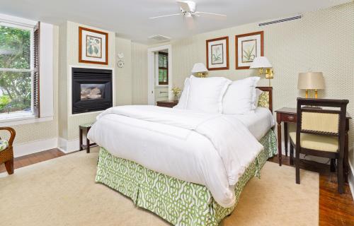 a bedroom with a large white bed and a fireplace at Rhett House in Beaufort