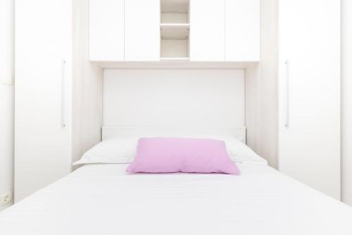 a white bed with a purple pillow on it at Apartments Tony in Mali Lošinj