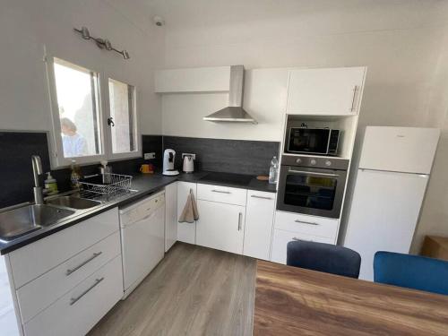 a kitchen with white cabinets and a sink and refrigerator at Appartement+Terrasse en Provence dans le Luberon in Apt