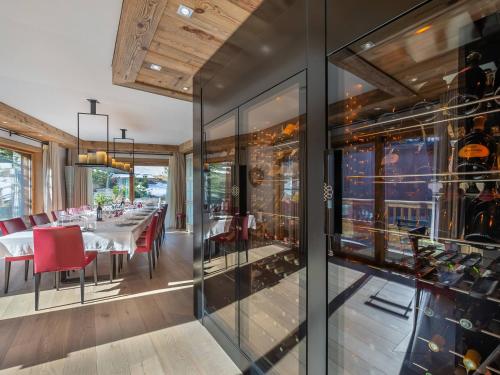 une salle à manger avec des murs en verre et une table avec des chaises rouges dans l'établissement Chalet de luxe avec demi-pension et espace bien-être à 2 min des pistes - FR-1-566-44, à Les Allues
