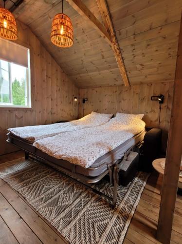 a bedroom with a large bed in a room with wooden walls at Unik overnatting i Stabbur/Minihus in Lunde