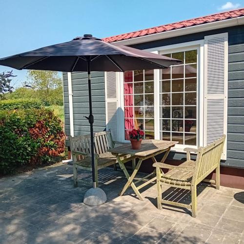 a table and chairs under an umbrella on a patio at Slapen op De Bult Green 2 persons in De Bult