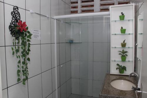 uma casa de banho em azulejos brancos com um lavatório e plantas em São Luís Hostel em São Luís