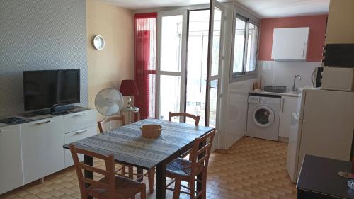 une cuisine et une salle à manger avec une table et un réfrigérateur dans l'établissement Lara 1 - Grand T2 Loggia Sans vis-à-vis Parking - Près centre-port, île des Loisirs, plage Richelieu, au Cap d'Agde