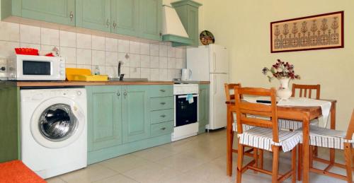 a kitchen with a washing machine and a table with chairs at ANEMOESSA APTS in Livadia